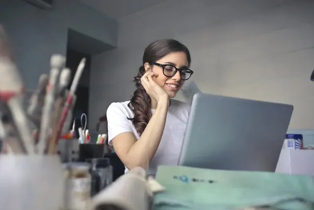 A designer smiling at her laptop in a bright studio